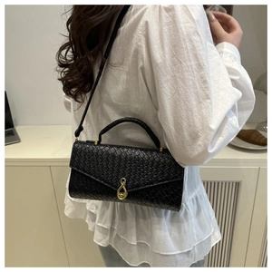 Detail of black crocodile embossed baguette bag with golden figure-eight clasp on model