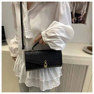Detailed view of the black embossed leather baguette bag with a gold metal lock closure