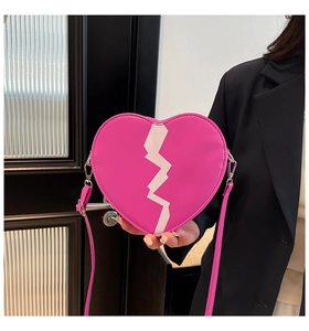 Détail du sac bandoulière rose en forme de cœur avec patch éclair blanc et boucles