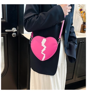 Close-up of pink heart-shaped crossbody bag with white zigzag pattern and slim strap