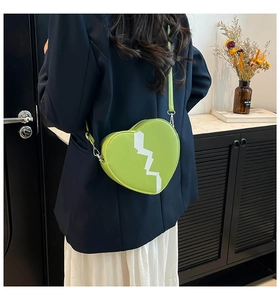 Détail d'un sac bandoulière en forme de cœur vert citron avec éclair blanc contrasté