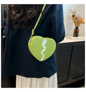 Détail du sac à main en forme de cœur vert avocat avec motif éclair blanc porté par le mannequin