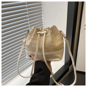 Detail of cream woven bucket bag with herringbone straw pattern and adjustable faux leather strap