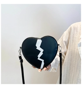 Détail du sac bandoulière noir en forme de cœur avec motif éclair et boucles argentées