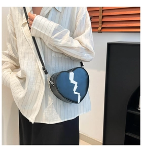 Modèle portant un sac bandoulière cœur en cuir noir avec motif éclair et bandoulière