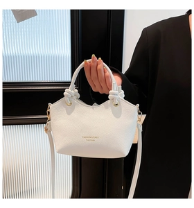Detail of white lychee leather bucket bag with knot handle and gold hardware