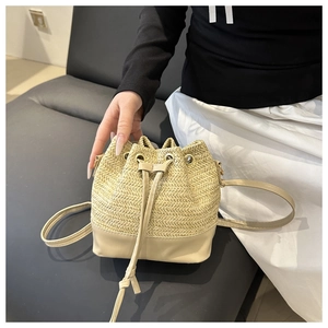 Detail of hand-held straw drawstring bucket bag with light khaki leather bottom base