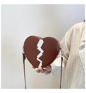 Détail du sac à bandoulière marron en forme de cœur avec motif blanc et boucles argent