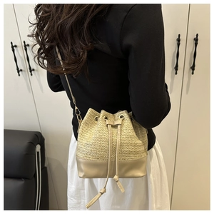 Detail of woven straw bucket bag with leather base and elegant gold chain strap