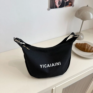 Black nylon crescent shoulder bag with white lettering YICAIAINI on a minimalist cabinet
