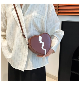 Brown heart-shaped crossbody bag with white lightning patch shown on a model