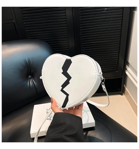 Détail d'un sac bandoulière en forme de cœur avec imprimé noir et finitions argentées