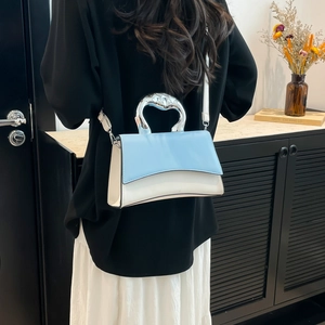 Blue and white deconstructed handbag with sculptural silver handle on shoulder