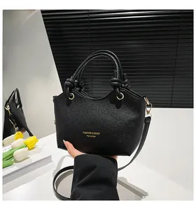 Detail of black lychee grain leather bucket bag with knotted handle and gold hardware