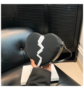 Détail d'un sac bandoulière en forme de cœur avec motif blanc et sangle réglable