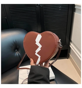 Détail du sac bandoulière marron en forme de cœur avec motif imprimé d'éclair blanc