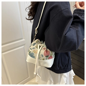 Ethnic style bucket bag with floral embroidery and white leather trim shown on model