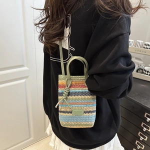 Rainbow striped woven crossbody bag with green leather straps and fashion label