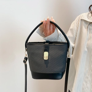Minimalist black bucket bag with diagonal woven texture and gold hardware for daily commute