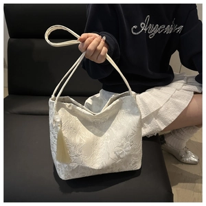 Detail of white butterfly jacquard tote bag with elegant tassel and lace texture