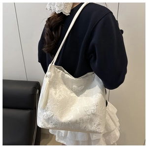 Detailed close-up of white lace shoulder bag featuring 3D butterfly appliques and long tassels