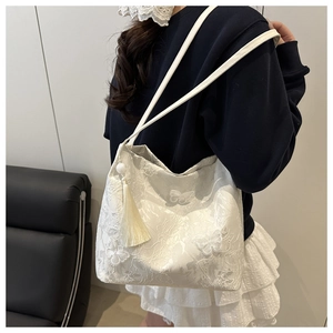 Détail du sac cabas en dentelle blanche avec broderie papillon et charm à franges