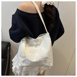Detail of white butterfly tote bag featuring textured 3D appliques and pearl tassel charm
