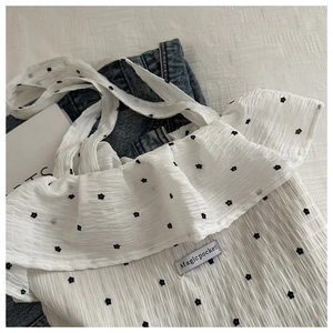 Detail of white ruffled tote bag with black floral print and Magic Pocket label