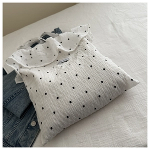 Detail of white ruffle tote bag with floral patterns and magic pocket brand label