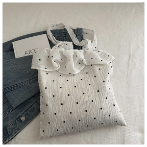 Detail of white textured canvas tote with ruffle trim and black floral pattern