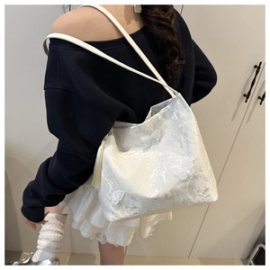 Detail of white butterfly tote bag with floral lace texture and side fringe tassel