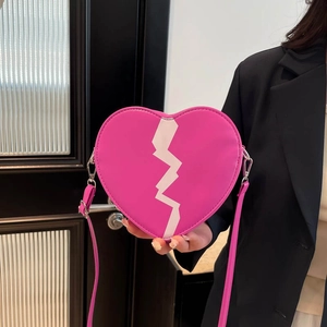 Sac à bandoulière fuchsia en forme de cœur avec motif cœur brisé porté par un mannequin