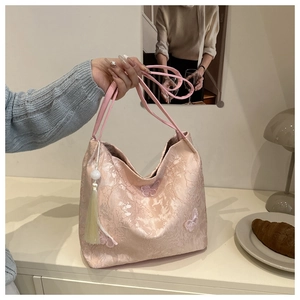 Detailed view of pink jacquard tote bag with butterfly applique and white tassel charm