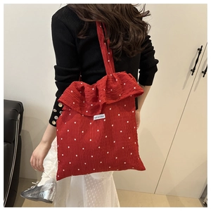 Detail of red floral tote bag with large ruffle edge and magic pocket woven label