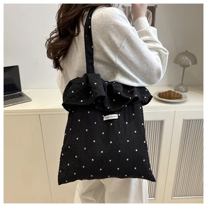 Close-up of black tote bag featuring ruffle trim and white floral star patterns