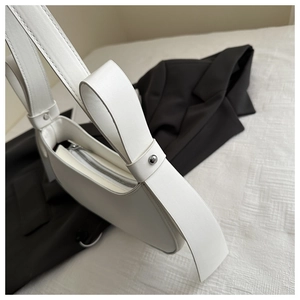 Detail of white leather underarm bag with silver rivets and wide strap design