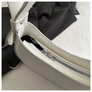 Close-up of white leather underarm bag with bow decoration and silver metal zipper
