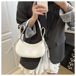 Detailed view of cream-white crescent shoulder bag featuring a decorative long bow knot