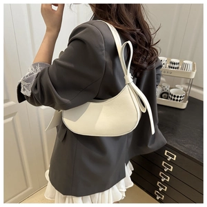 White leather half-moon shoulder bag with minimalist buckle worn by a female model