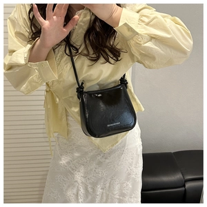 Dettaglio borsa a secchiello in pelle nera con scritta Fashion & Bags sul fondo