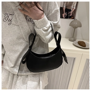Detail of black crescent shoulder bag with bow ribbons and silver zipper closure