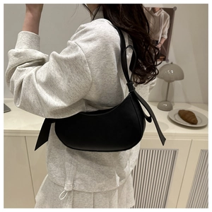 Detail of a black crescent hobo bag with a knotted strap shown in a lifestyle setting