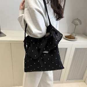 Black floral tote bag with large bow detail and ruffle texture shown in lifestyle setting