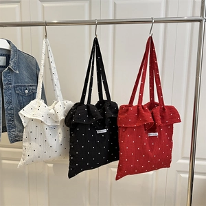 Floral tote bags with ruffle trim in black, white and red colors hanging on a metal rack