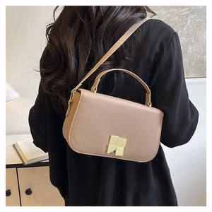 Detail of elegant beige crossbody bag with premium gold metal lock on a fashion model