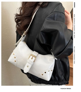 Detail view of white leather shoulder bag with vintage gold studs and buckle on model