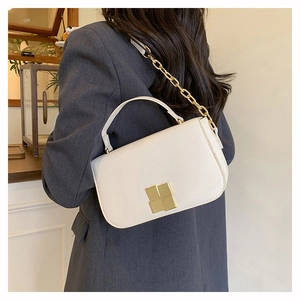Detail of cream white rectangular bag with gold geometric clasp and chunky metal chain strap