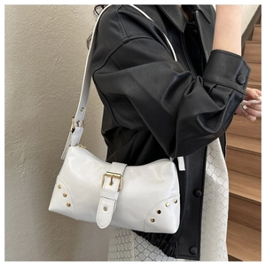 Sac à bandoulière blanc avec rivets dorés et boucle sur une veste en cuir noir