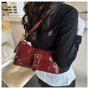 Dettaglio della borsa a spalla in pelle lucida rosso scuro con borchie e fibbia vintage