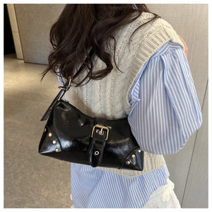 Detail view of black glossy shoulder bag with vintage gold buckle and metal rivets